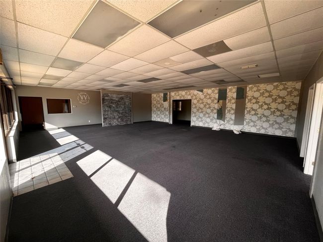 Unfurnished living room featuring dark carpet, a drop ceiling, and baseboards | Image 4
