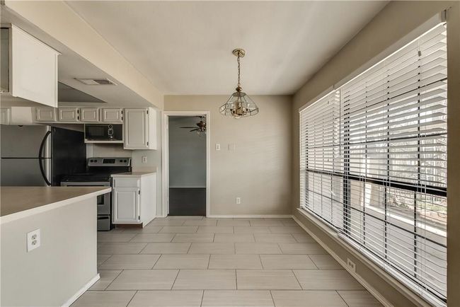 Kitchen featuring appliances with stainless steel finishes, ceiling fan, decorative light fixtures, white cabinets, and light countertops | Image 6
