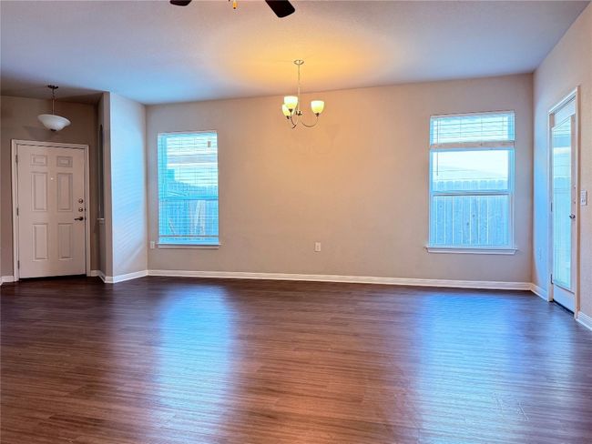 Empty room featuring ceiling fan, dark wood-style flooring, a chandelier, and baseboards | Image 6