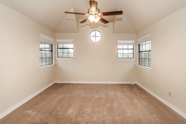 Empty room featuring light carpet, ceiling fan, vaulted ceiling, and plenty of natural light | Image 10