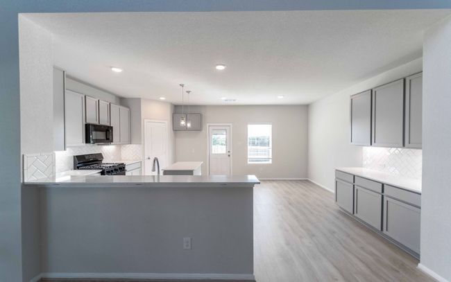 Kitchen featuring black appliances, decorative backsplash, light wood-style floors, a peninsula, and recessed lighting | Image 6