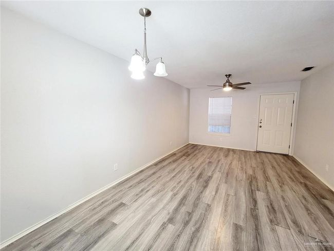 Unfurnished room with light wood-style floors, ceiling fan, and a chandelier | Image 12