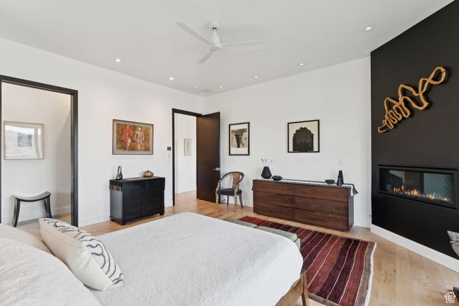Bedroom with light wood finished floors, a large fireplace, ceiling fan, and recessed lighting | Image 25