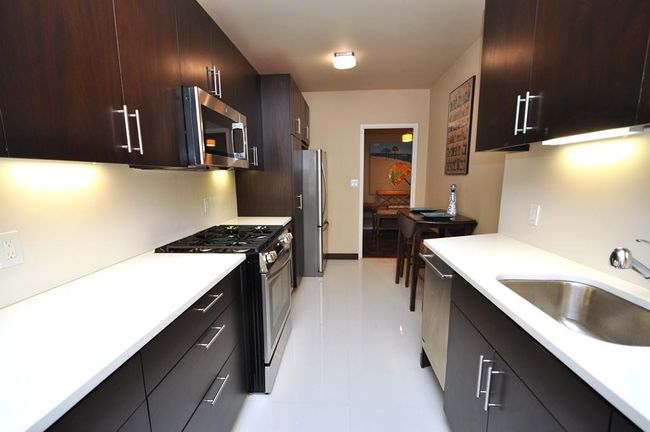 Fully renovated Eat-in-Kitchen has custom mocha colored cabinets, Quarts counters and stainless steel appliances including a wine cooler, dishwasher, microwave, range and refrigerator. | Image 12