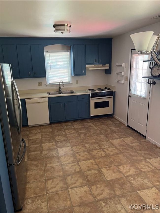 Kitchen with dishwashing machine, refrigerator, stove, blue cabinets, and range hood | Image 15