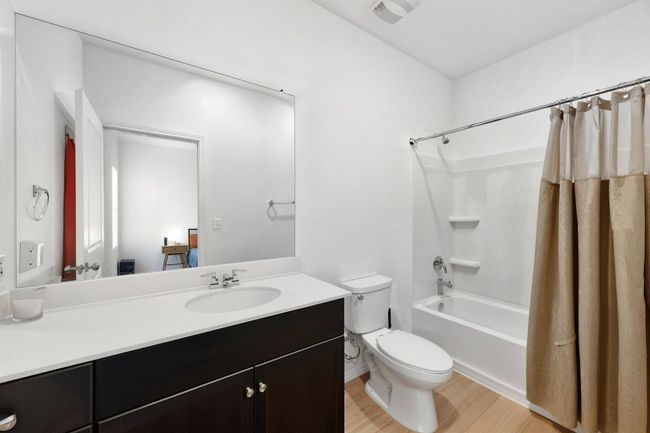 Full bathroom with toilet, wood finished floors, shower / bath combo with shower curtain, and vanity | Image 16