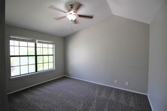 Empty room featuring ceiling fan, dark colored carpet, and lofted ceiling | Image 11