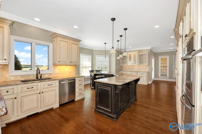 Wood flooring, wood cabinetry, kitchen island with bar seating, recessed lighting | Image 15