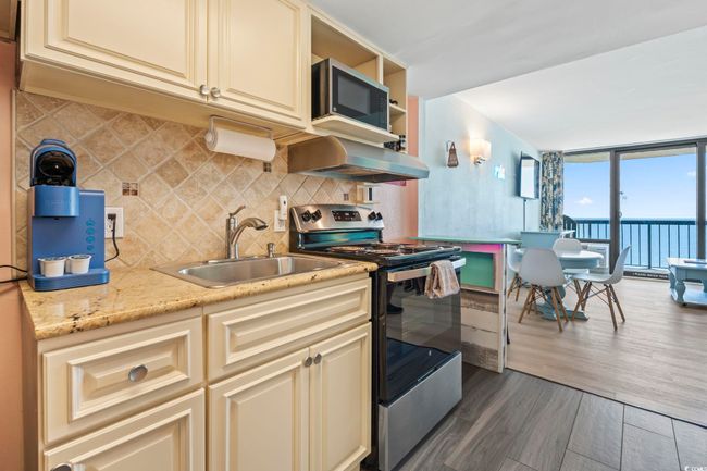 Kitchen featuring cream cabinets, stainless steel appliances, extractor fan, tasteful backsplash, and wood finished floors | Image 9