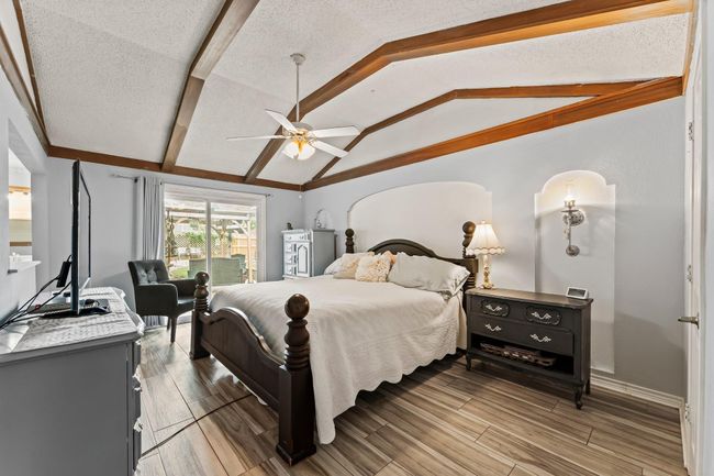 Primary retreat features arched ceiling with wood beams and a sliding glass door to the serene back yard. | Image 16