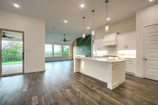 Kitchen featuring a ceiling fan, custom exhaust hood, dark wood finished floors, backsplash, and recessed lighting | Image 5