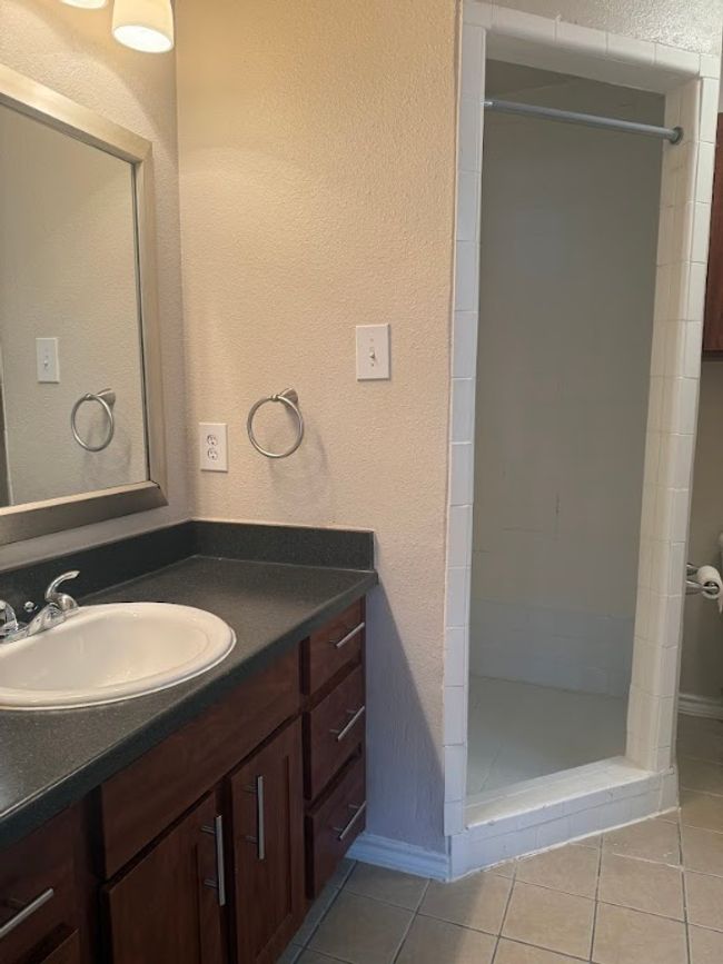 Full bath featuring vanity, a shower stall, tile patterned flooring, and a textured wall | Image 19