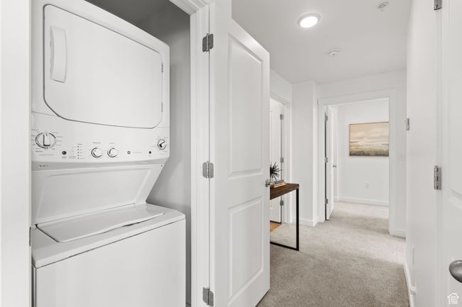 Laundry room featuring light carpet and estacked washer and dryer | Image 17