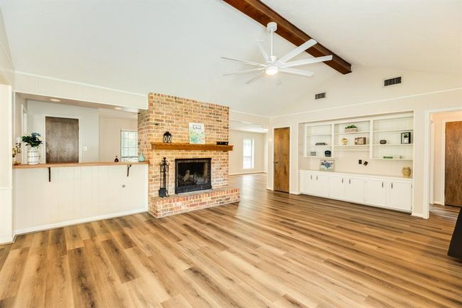 Vaulted ceiling with a large ceiling fan keep this space cool in the summer. Sit and relax in front of the cozy fire in the raised hearth brick fireplace in the winter. Expansive built in shelving unit just waiting to display all your treasures. LVP flooring throughout the living areas. | Image 12