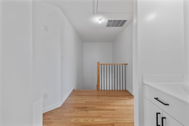 Hallway featuring visible vents, a sink, an upstairs landing, light wood-style floors, and baseboards | Image 22
