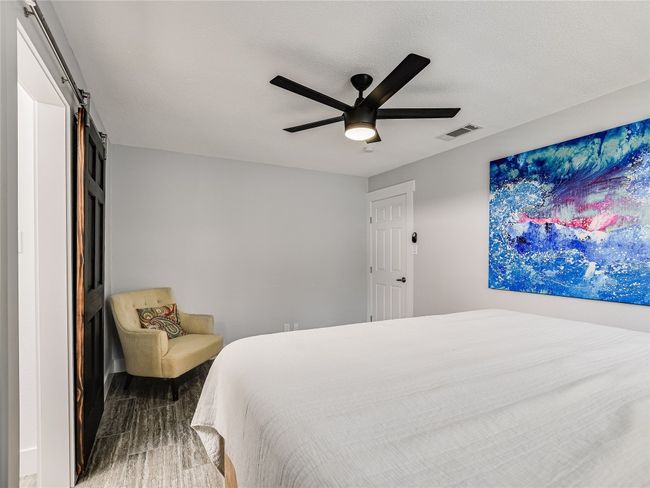 Bedroom with a ceiling fan, a barn door, and visible vents | Image 11