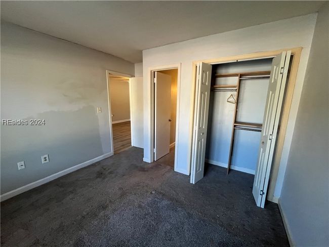 Unfurnished bedroom featuring a closet and dark colored carpet | Image 12