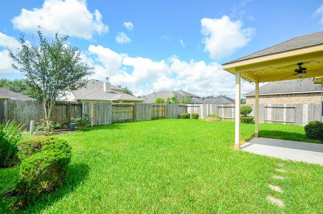 Spacious backyard with lush green lawn, privacy fencing, and a covered patio perfect for outdoor relaxation and entertainment. | Image 30