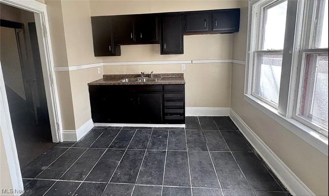 Kitchen featuring a sink, baseboards, dark cabinetry, and dark tile patterned flooring | Image 5