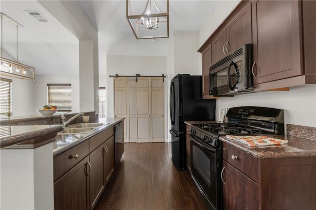 Kitchen with black appliances, a sink, dark wood-style floors, and pendant lighting | Image 7