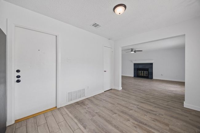 Unfurnished living room with a tiled fireplace, wood finished floors, visible vents, and a textured ceiling | Image 15
