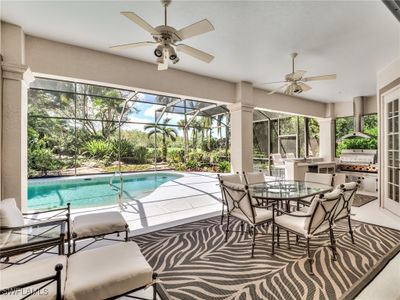 View of swimming pool with glass enclosure, a grill, ceiling fan, and a patio area | Image 3