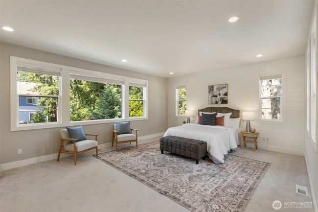 The serene primary suite is bathed in natural light, with expansive windows framing views of lush greenery. Spacious and elegant, it features a cozy sitting area and soft neutral tones, creating a peaceful retreat to unwind and recharge. | Image 27
