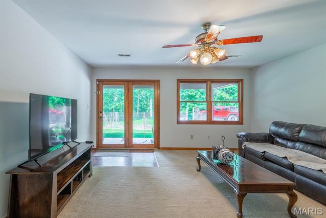 Carpeted living room with a ceiling fan and baseboards | Image 5