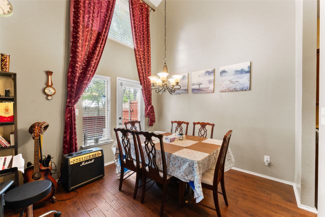 Dining space with a high ceiling, hardwood / wood-style flooring, baseboards, and a chandelier | Image 9