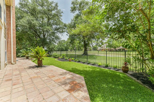 The patio extends across the back of the home, along with the tasteful and manicured landscaping | Image 43