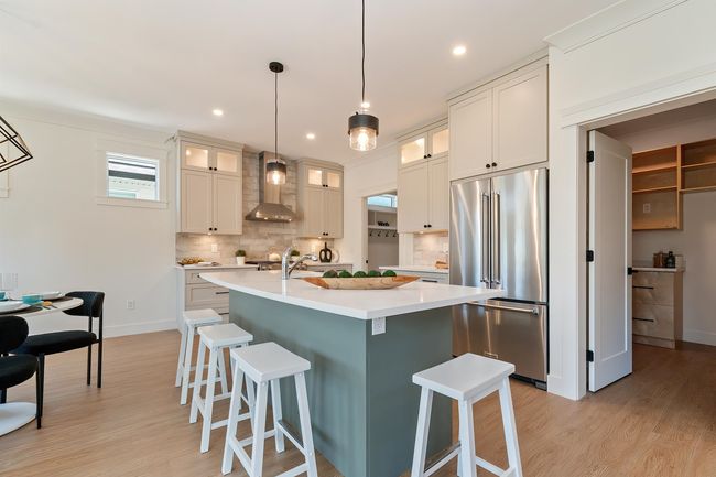 Kitchen with high quality fridge, wall chimney range hood, decorative backsplash, light wood-style flooring, and recessed lighting | Image 6