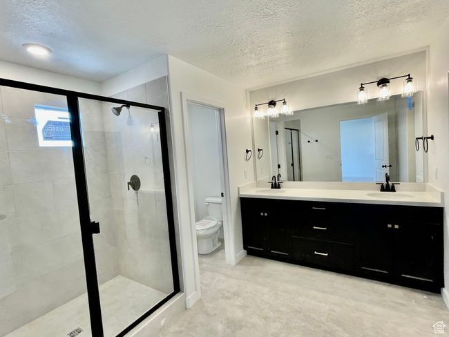Full bathroom with a stall shower, double vanity, and a textured ceiling | Image 12