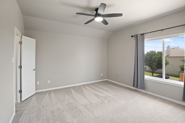 Carpeted empty room with vaulted ceiling, a ceiling fan, and baseboards | Image 24