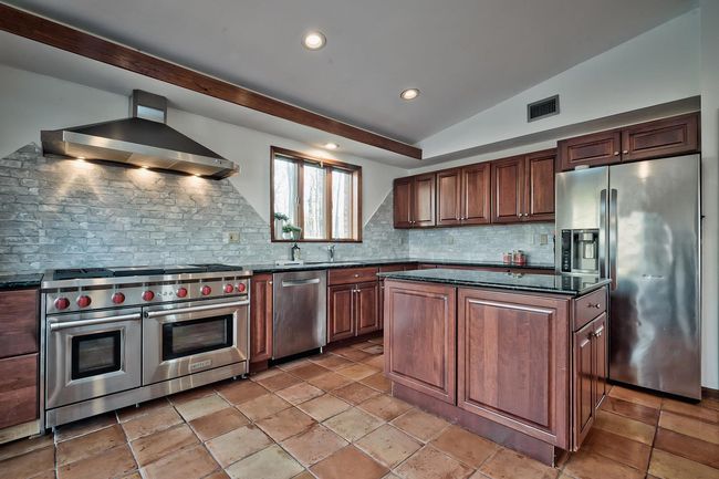 Kitchen with vaulted ceiling, stainless steel appliances, visible vents, and wall chimney exhaust hood | Image 6