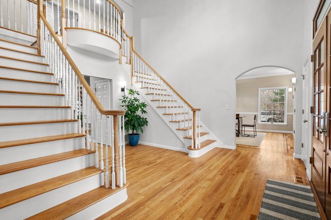 Step into a grand two-story foyer featuring a sweeping double staircase, gleaming hardwood floors, and timeless architectural elegance. | Image 20