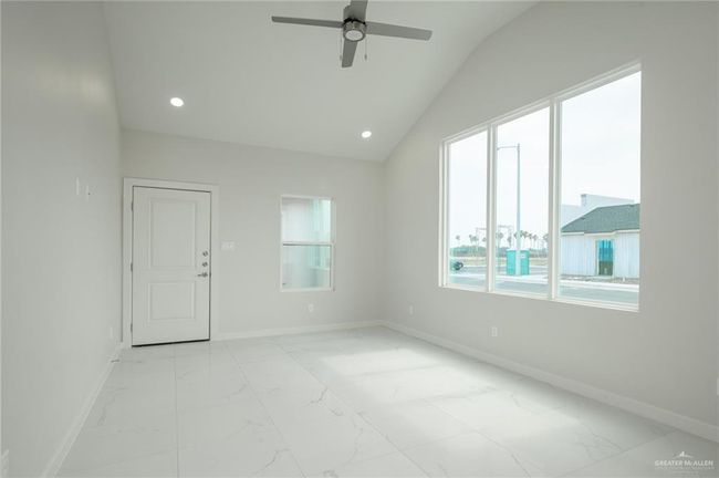 Spare room featuring light marble finish floors, a ceiling fan, baseboards, recessed lighting, and lofted ceiling | Image 8
