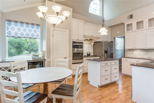 Kitchen featuring appliances with stainless steel finishes, dark countertops, backsplash, white cabinets, and ornamental molding | Image 7