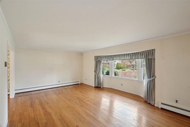 Spare room with a baseboard heating unit, crown molding, and light wood-type flooring | Image 11