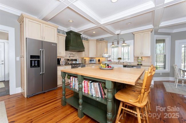 Bookshelf feature at center island; Decorative Hood above Pot-Filling Station and 6-burner gas range/oven. | Image 10