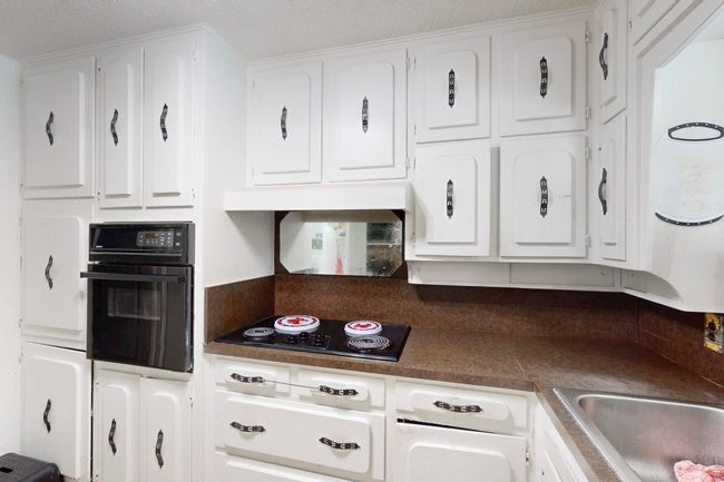 Kitchen with a sink, white cabinetry, and black appliances | Image 13