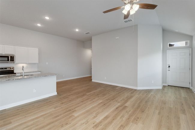 Unfurnished living room with light wood finished floors, visible vents, baseboards, and a sink | Image 6