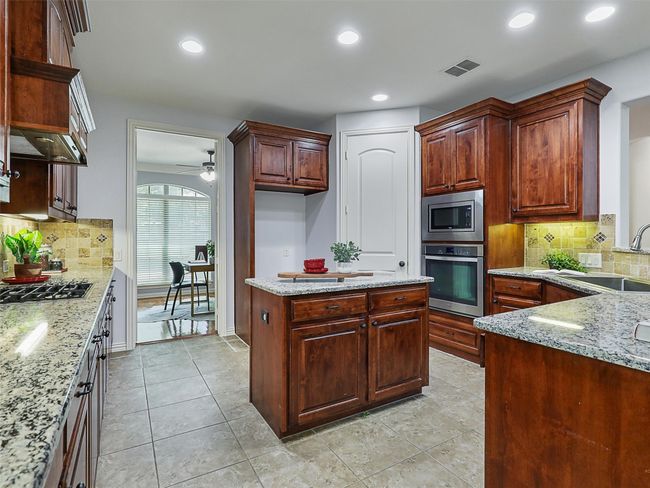 Kitchen featuring appliances with stainless steel finishes, ceiling fan, decorative backsplash, light stone countertops, and recessed lighting | Image 9