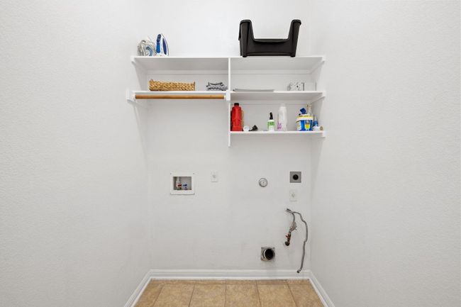 Laundry area with gas dryer hookup, hookup for a washing machine, electric dryer hookup, and light tile patterned flooring | Image 11