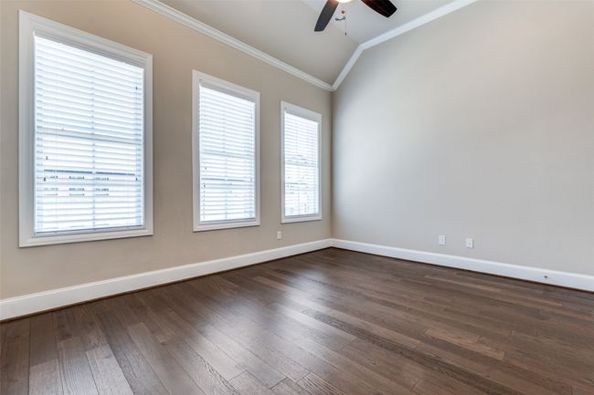 Empty room featuring ornamental molding, vaulted ceiling, ceiling fan, and dark wood-style floors | Image 26