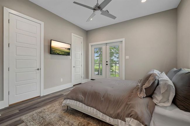 A generously sized bedroom featuring a private ensuite bathroom and a balcony overlooking the serene backyard and picturesque lake views. Two bedrooms are located on the second floor. | Image 33