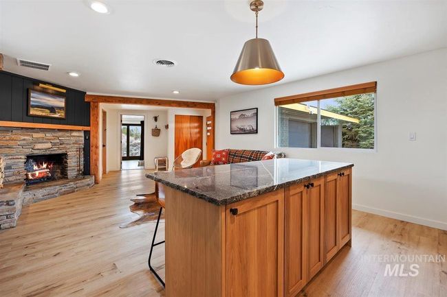 Kitchen with a breakfast bar, light wood finished floors, a kitchen island, a fireplace, and recessed lighting | Image 38