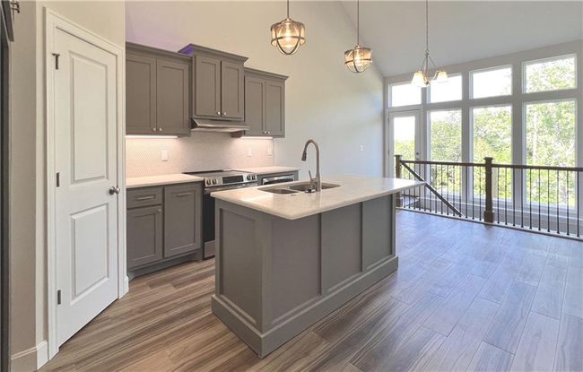 Kitchen featuring gray cabinetry, electric range, backsplash, light countertops, and high vaulted ceiling | Image 18