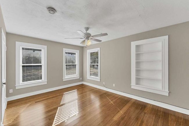 Empty room featuring built in features, baseboards, a ceiling fan, and hardwood / wood-style flooring | Image 15