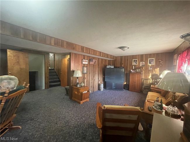 Living room with dark colored carpet and wooden walls | Image 19