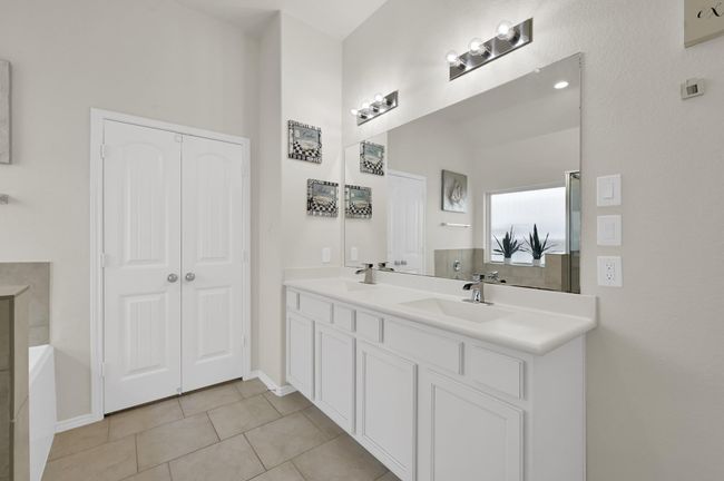 The primary bath showcases white cabinetry with a double sink, and a strategically placed mirror to reflect the most amount of light, making the room feel more open. | Image 17